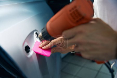 Téléchargez les photos : Sèche-linge industriel dans les mains d'un réparateur, il colle un film anti-gravier sur les portes de la voiture - en image libre de droit