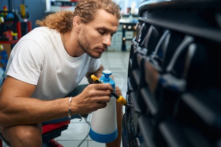 Foto de Proceso de detalle del coche en un taller de reparación de automóviles, un mecánico de automóviles limpia las rejillas - Imagen libre de derechos