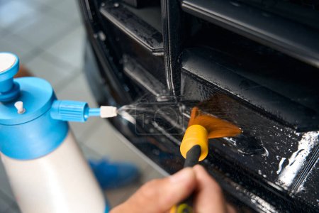 Photo for Man cleans a car air duct with a special brush and also uses a spray bottle - Royalty Free Image