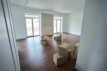 Téléchargez les photos : Chambre moderne vide confortable maison de ville avec différents objets dans des boîtes en carton sur le sol pendant le déplacement - en image libre de droit