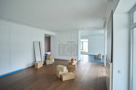 Photo for Empty modern comfortable sunny townhouse with variety objects in cardboard boxes on floor during moving - Royalty Free Image