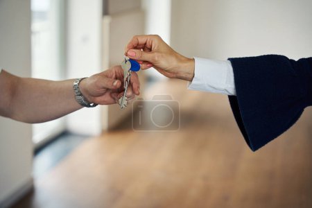 Maklerin übergibt dem Käufer die Schlüssel für ein neues Ferienhaus, das Zimmer ist geräumig und leer