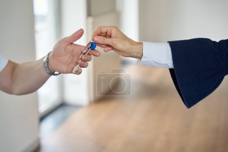 Verkaufsleiter übergibt dem Käufer die Schlüssel für ein neues Häuschen, der Raum ist geräumig und leer