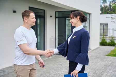 Photo for Sales manager welcomes the buyer at the new cottage, landscaped on the territory - Royalty Free Image