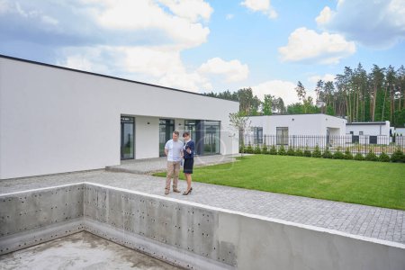 Téléchargez les photos : Femme agent immobilier et client inspectent la piscine près d'une nouvelle maison, il y a une pelouse verte dans la cour - en image libre de droit
