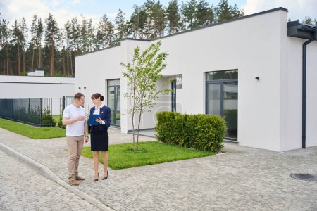Verkaufsleiter zeigt dem Käufer Unterlagen für ein neues Haus, Landschaftsplanung auf dem Gebiet