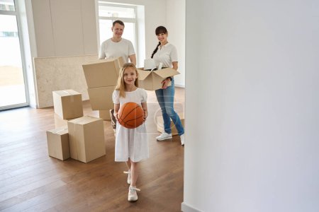 Téléchargez les photos : Les parents et leur fille déménagent dans une nouvelle maison de campagne, les gens déménagent des boîtes de choses - en image libre de droit