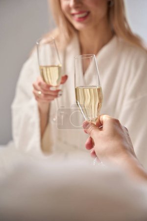 Téléchargez les photos : Couple romantique parlant joliment autour d'une coupe de champagne, les gens en peignoirs moelleux - en image libre de droit