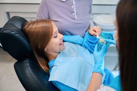 Photo for Girl holds a model of dentition and a toothbrush in her hands, she is at an appointment with a hygienist - Royalty Free Image