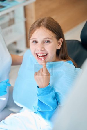 Foto de Niño muestra sus dientes en la recepción en el dentista, la niña sonríe - Imagen libre de derechos