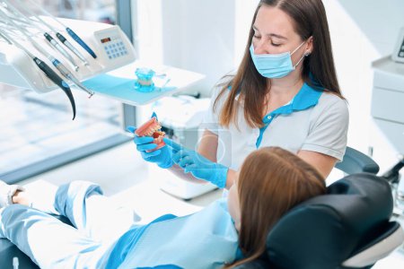 Dentist teaches child oral hygiene using dummy jaws