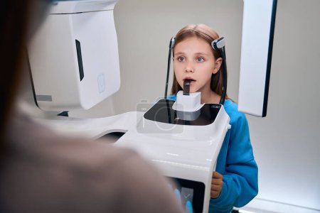 Téléchargez les photos : Médecin faisant des radiographies dentaires à un jeune patient, femme portant des gants de protection - en image libre de droit