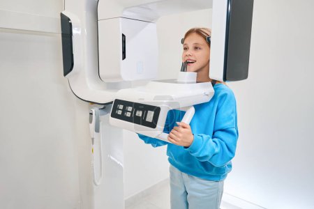 Téléchargez les photos : Jeune patiente soumise à une radiographie dentaire, un équipement moderne est utilisé - en image libre de droit