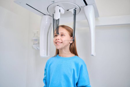 Téléchargez les photos : Fille est fixé pour une radiographie dentaire, équipement moderne est utilisé - en image libre de droit