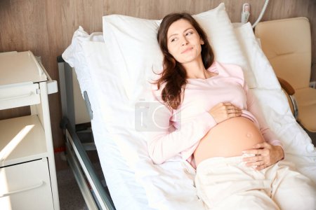Foto de Calma mujer embarazada relajada en la cama en la sala de la clínica - Imagen libre de derechos