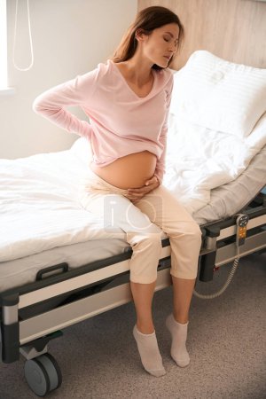Téléchargez les photos : Femme enceinte caucasienne avec des contractions douloureuses pendant le processus d'accouchement à l'hôpital - en image libre de droit