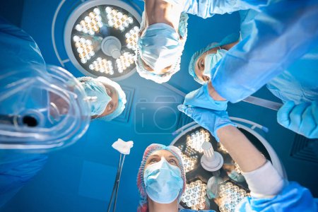 Téléchargez les photos : Chirurgien et assistants i salle d'opération effectuant une opération dans une clinique médicale moderne - en image libre de droit