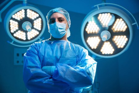 Foto de Cirujano de confianza de pie con los brazos cruzados en el quirófano en el hospital en el quirófano moderno - Imagen libre de derechos