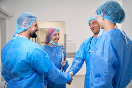 Téléchargez les photos : Équipe médicale de médecins chirurgiens poignée de main dans le couloir à l'hôpital - en image libre de droit