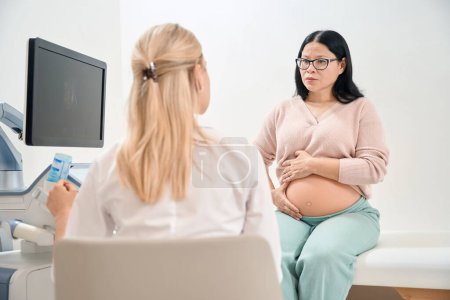 Schockierte asiatische Frau hört Nachrichten über eingefrorene Schwangerschaft, Gynäkologin sieht den Tod des Fötus im Mutterleib auf dem Ultraschall