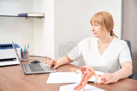 Photo for Qualified woman gynecologist reading articles about treatment in internet, fighting against infertility, looking for new medications with proven effectiveness - Royalty Free Image