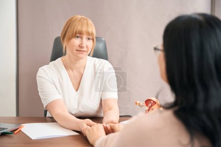 Photo for Back view grateful woman holding hands of female gynecologist who examining her health of reproductive system, happy to be healthy and to have opportunity to have a baby - Royalty Free Image