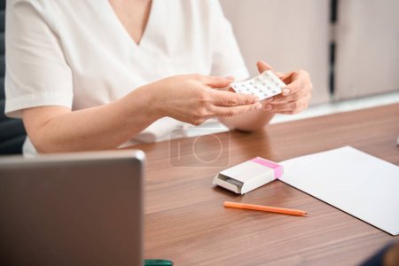 Photo for Close-up woman gynecologist holding and showing blister with little white tablets, advising female patient to start the hormonal therapy to normalize the level in body - Royalty Free Image