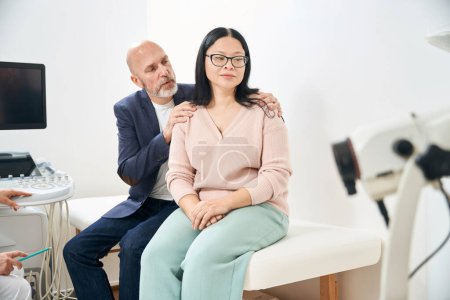 Caring husband calming down and supporting his upset depressed adult wife after ultrasound diagnostic in reproductology clinic, failed attempt to get a baby, miscarriage