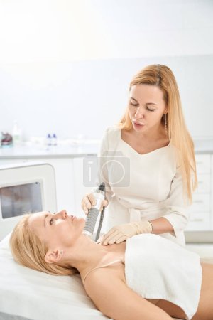 Foto de Dermatólogo que lleva microneedle rf-lifting procedimiento en el cuello de los clientes, utilizando un dispositivo que crea daño microscópico a la piel con 36 como agujas electrodos recubiertos de oro - Imagen libre de derechos