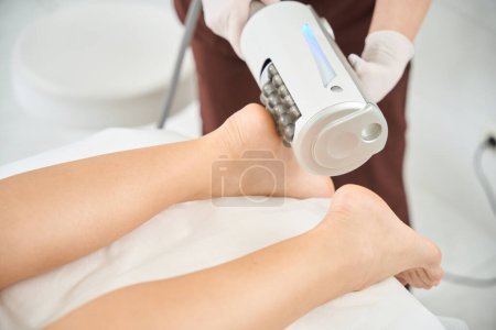 Photo for Skilled phlebologist applying endosphere therapy to the clients feet and heels, relieving muscle spasms and pain after intense training and physical exertion, improving muscle trophism - Royalty Free Image