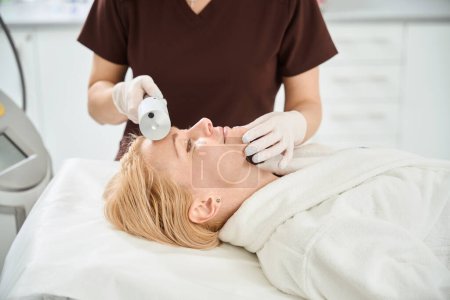 Dermatocosmétologue rajeunissant la peau sur le visage et le front jolie femme avec l'aide de la thérapie endosphère, resserrement et tonifier les muscles et la peau, clinique de médecine esthétique