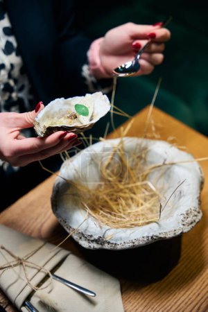Foto de Mujer recortada sosteniendo la freír ostra y cuchara en las manos en la mesa en el restaurante. Concepto de sabrosa alimentación saludable - Imagen libre de derechos