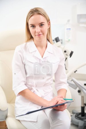 Photo for Female caucasian gynecologist with clipboard looking at camera during work in clinic. Concept of healthcare - Royalty Free Image