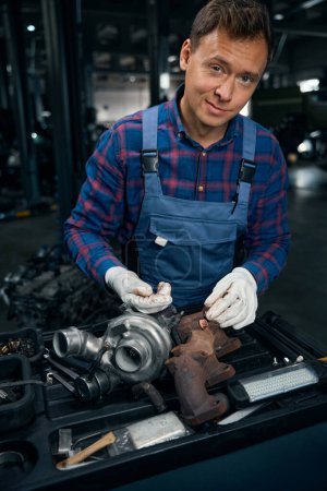 Foto de Hombre con ropa protectora realizando mantenimiento en el dispositivo para aumentar la potencia del motor en el centro de servicio del vehículo - Imagen libre de derechos