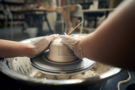 Foto de Mujer irreconocible haciendo olla de cerámica en la rueda de cerámica en el taller - Imagen libre de derechos