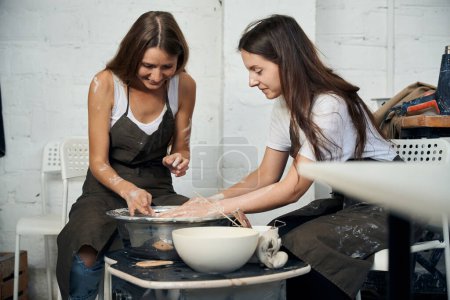 Photo for Women making ceramic plate sculpting in workshop on potters wheel in pottery workshop - Royalty Free Image