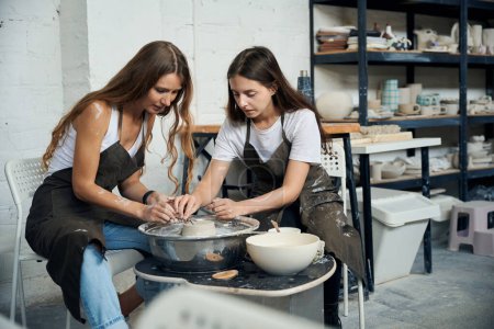 Foto de Alfareros hembras haciendo platos de arcilla sobre rueda de cerámica en estudio de cerámica - Imagen libre de derechos
