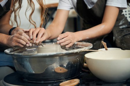 Téléchargez les photos : Femmes potiers méconnaissables faisant de la céramique sur roue de poterie dans un atelier créatif - en image libre de droit