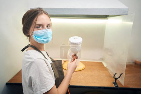 Téléchargez les photos : Femme potier tenant pulvérisation étant prêt à aérographe produits d'argile en studio créatif - en image libre de droit