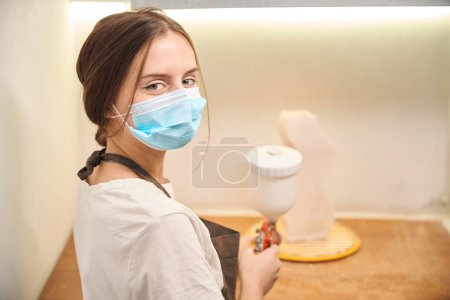 Photo for Pottery artisan woman worker using airbrush to paint ceramic products in workshop - Royalty Free Image