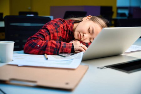 Téléchargez les photos : Jeune femme asiatique fatiguée responsable informatique dormant au bureau de travail dans le bureau de coworking. Concept de travail indépendant ou à distance moderne - en image libre de droit