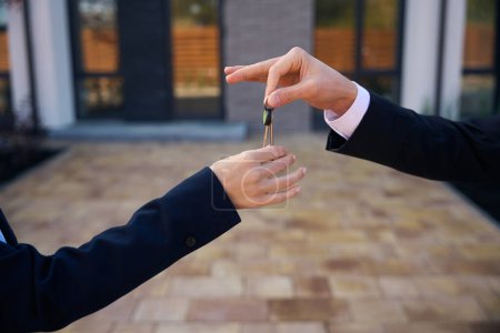Cropped photo of woman hand getting keys from man hand near the house
