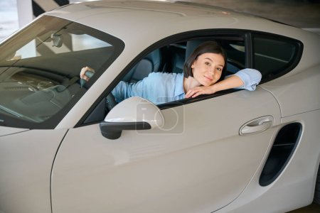 Photo for Happy smiling female sitting in new car, holding rudder, smiling and looking at camera - Royalty Free Image