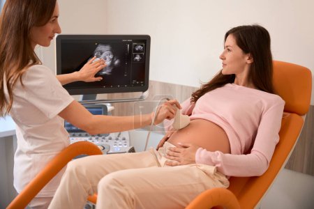Téléchargez les photos : Femme médecin échographie mouvement sonde sur les femmes enceintes estomac à l'hôpital - en image libre de droit