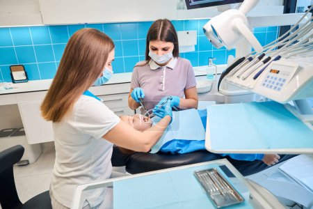 Dentist gives an injection with an anesthetic to a girls gums, an assistant helps the doctor