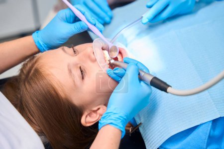 Téléchargez les photos : La dent des adolescentes est percée dans une clinique dentaire en utilisant un équipement moderne spécial - en image libre de droit