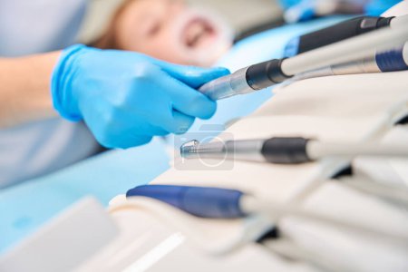 Dentist uses sterile drill bits, woman wearing protective gloves