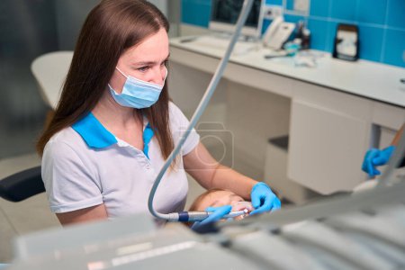 Female dentist removes plaque from a teenage girl, modern dental equipment is used