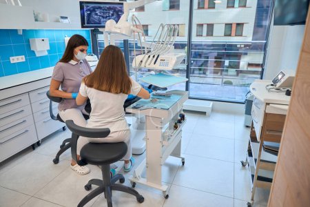 Foto de Los médicos en el lugar de trabajo en un consultorio dental, hay una gran cantidad de equipos modernos en la habitación - Imagen libre de derechos