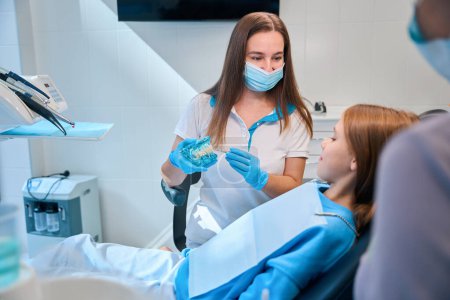 Foto de Chica teniendo una consulta con un higienista dental en una clínica moderna, una mujer que trabaja con un asistente - Imagen libre de derechos